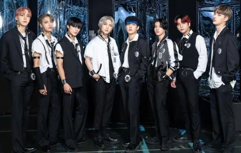 ATEEZ members in synchronized black and white stage outfits, representing their theatrical performance energy.