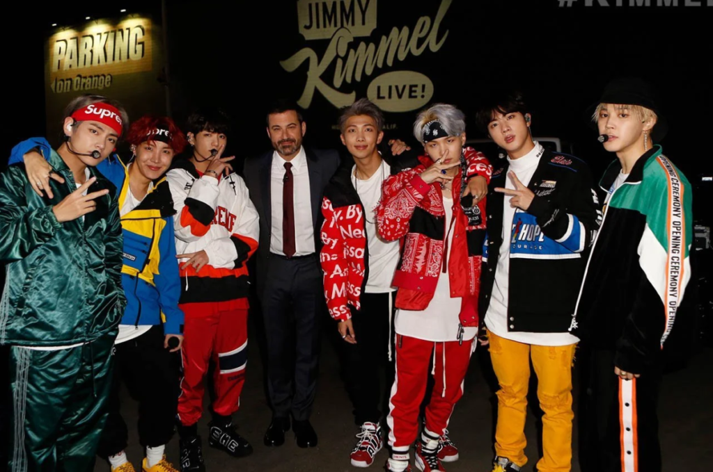BTS with Jimmy Kimmel backstage wearing colorful street fashion and Supreme headbands