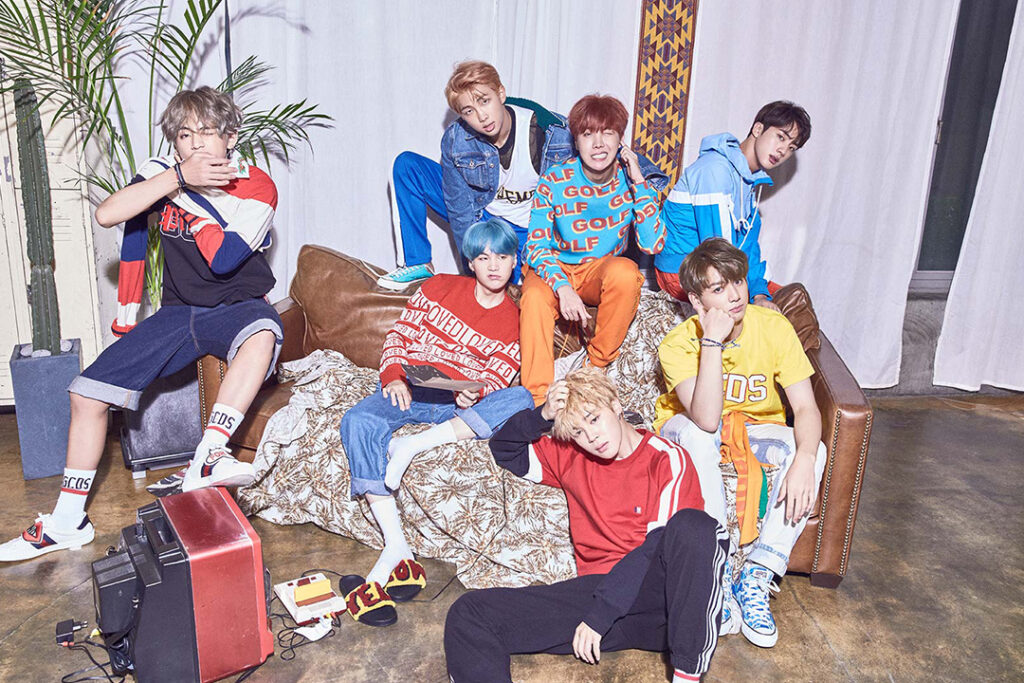 BTS members RM, Jin, Suga, j-hope, Jimin, V, and Jungkook in colorful retro outfits for DNA promotions